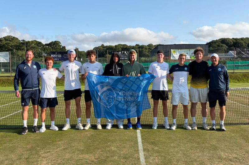 Mne's team holding flag on grass tennis court