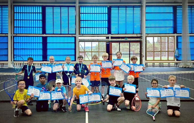Children with tennis rackets adn certificates on tennis court
