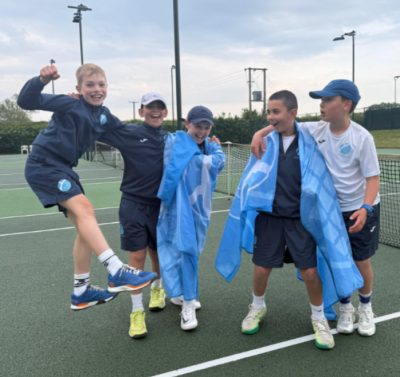 Boys on tennis court celebrating and holding flag