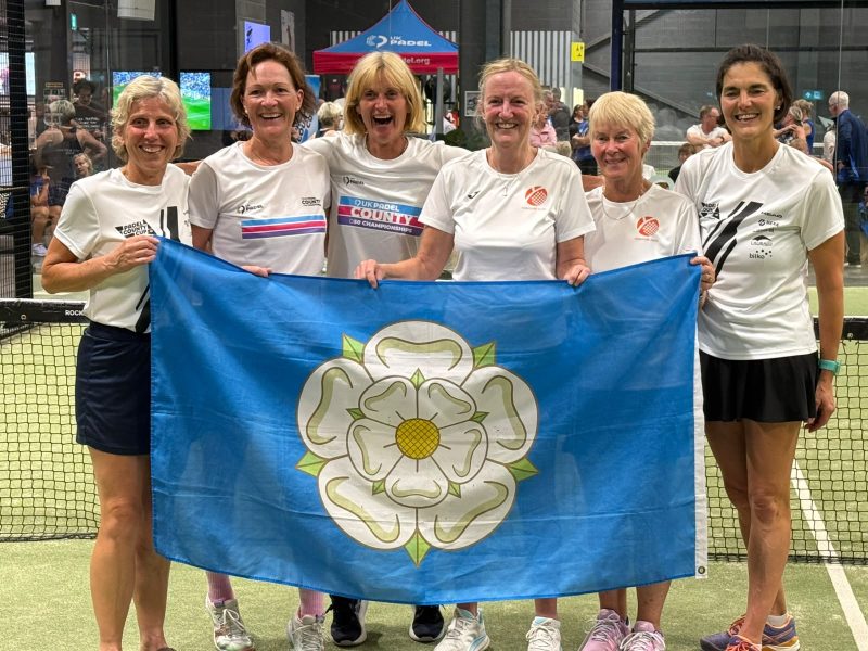 Women holding Yorkshire flag on padel court
