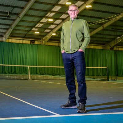 Man standing on tennis court looking into camera
